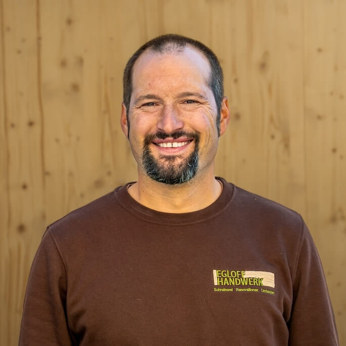 Team Egloff Handwerk | Schreinermeister Andy mit Holzbrett als Hintergrund