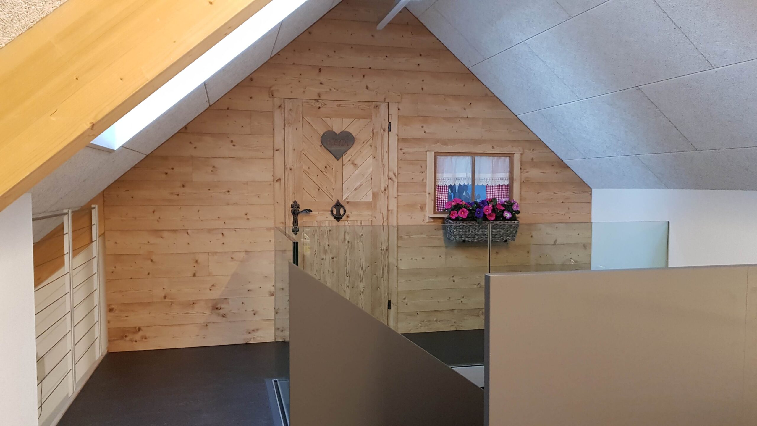 Umbau & Innenausbau | eine Altholzwand mit Tür iimd Fenster und Blumen