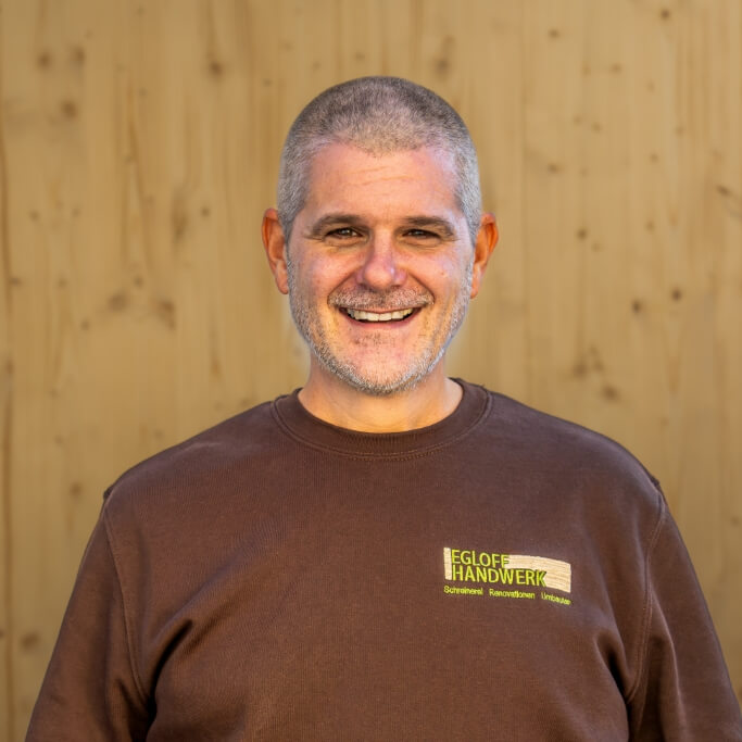 Team Egloff Handwerk | Alex mit Holzbrett als Hintergrund