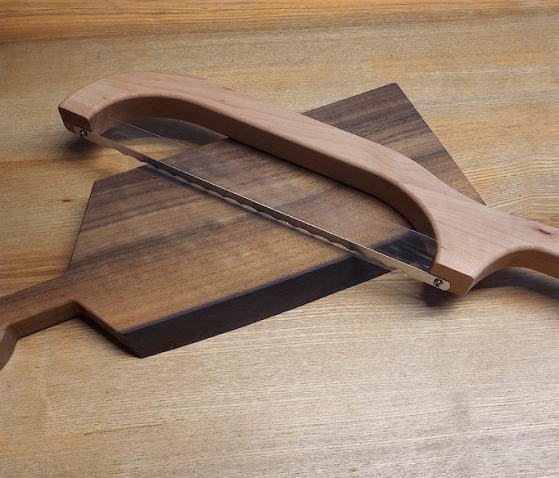 Brotsäge aus Holz auf einem Schneidebrett